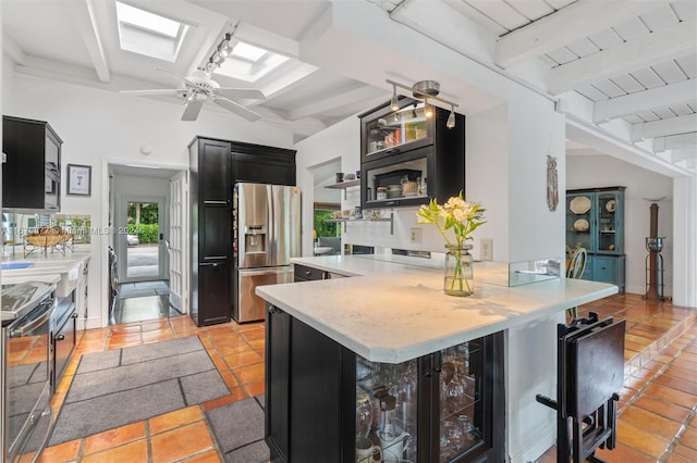 kitchen with stainless steel fridge, beamed ceiling, a kitchen bar, stove, and a skylight