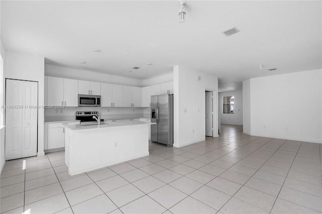 kitchen with white cabinets, a kitchen island with sink, stainless steel appliances, and light tile patterned floors