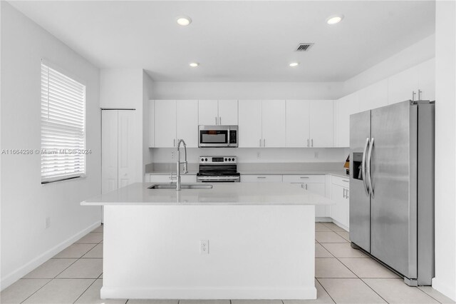 kitchen with white cabinets, a center island with sink, appliances with stainless steel finishes, and sink