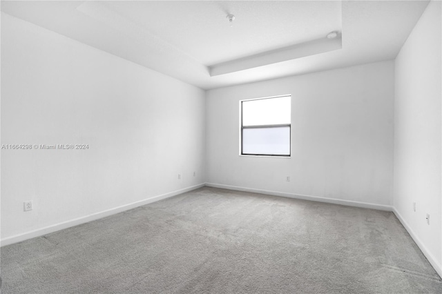 carpeted empty room featuring a raised ceiling