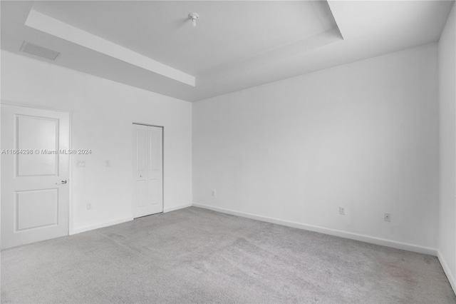 carpeted spare room with a tray ceiling