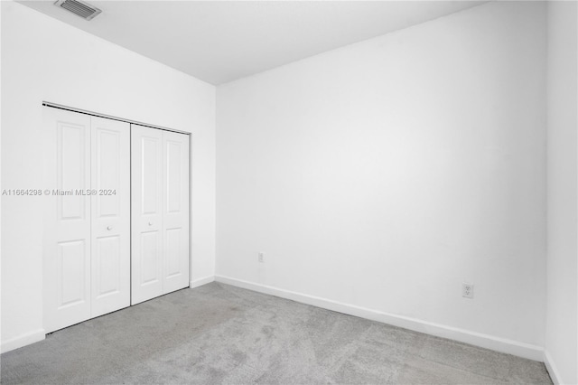 unfurnished bedroom with light carpet and a closet