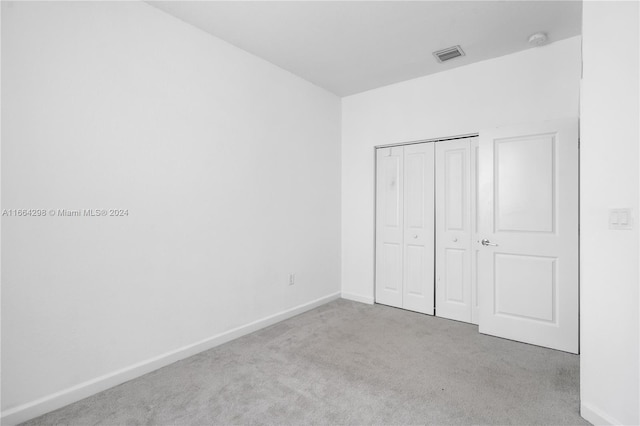 unfurnished bedroom with light carpet and a closet