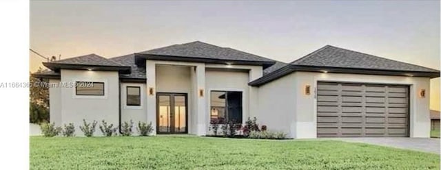 prairie-style house featuring a garage and a front lawn