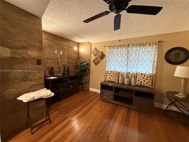 living area with crown molding, ceiling fan, wood-type flooring, and a textured ceiling