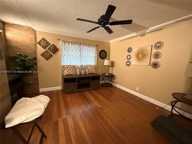 sitting room with dark wood-type flooring, ceiling fan, ornamental molding, and a textured ceiling