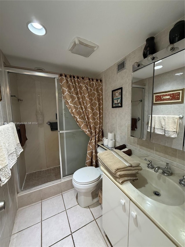 bathroom with vanity, tile walls, tile patterned flooring, a shower with shower door, and toilet