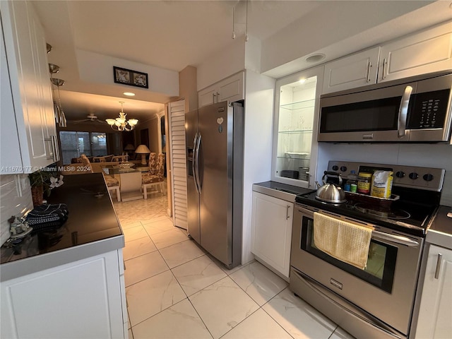 kitchen featuring appliances with stainless steel finishes, backsplash, a chandelier, and white cabinets