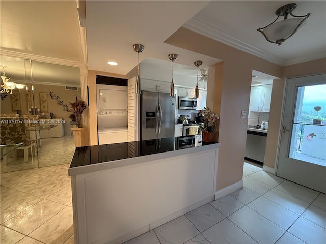 kitchen with stacked washer and clothes dryer, appliances with stainless steel finishes, hanging light fixtures, and white cabinets