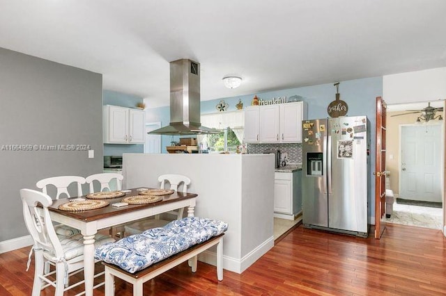 kitchen featuring stainless steel fridge, decorative backsplash, white cabinetry, range hood, and dark hardwood / wood-style floors