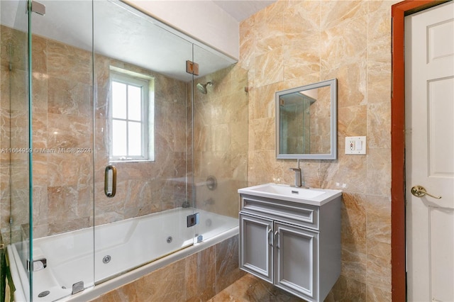 bathroom with vanity, tile walls, and combined bath / shower with glass door