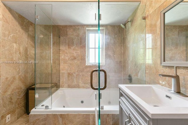 bathroom featuring bath / shower combo with glass door, vanity, and tile walls