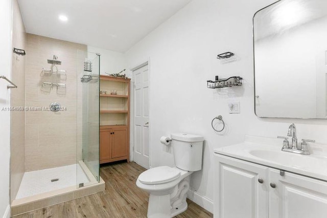 bathroom featuring a tile shower, vanity, toilet, and hardwood / wood-style flooring