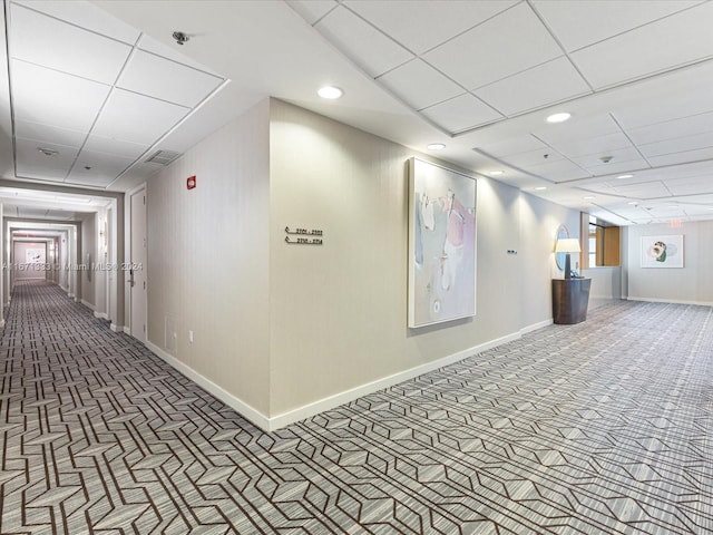 hallway with a paneled ceiling and carpet floors