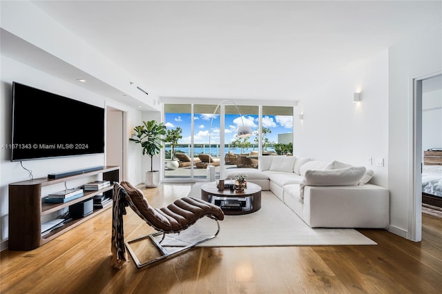 living room featuring a wall of windows, a water view, and hardwood / wood-style floors