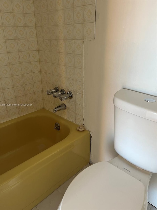 bathroom with a tub to relax in and toilet