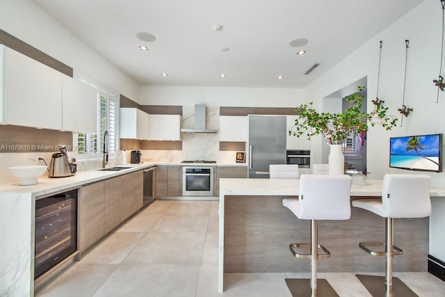 2382 Alton Rd, Miami Beach, FL 33140 - kitchen featuring appliances with stainless steel finishes, a sink, beverage cooler, wall chimney exhaust hood, and backsplash