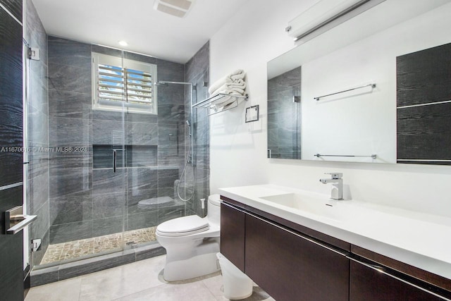 bathroom featuring tile patterned floors, vanity, toilet, and a shower with shower door