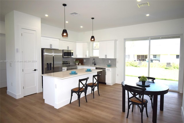 kitchen with white cabinets, dark hardwood / wood-style flooring, stainless steel appliances, and a kitchen island