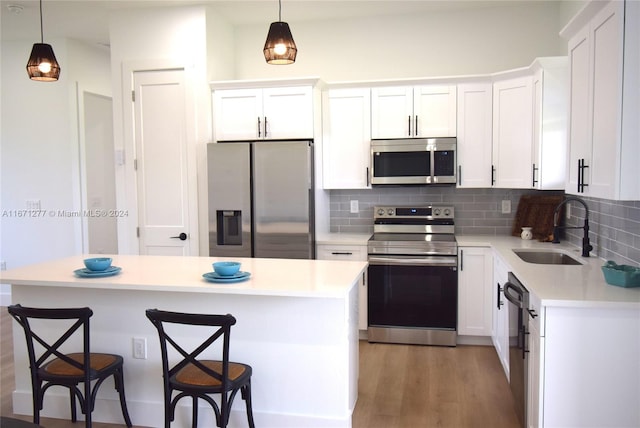 kitchen featuring white cabinets, sink, stainless steel appliances, and hanging light fixtures