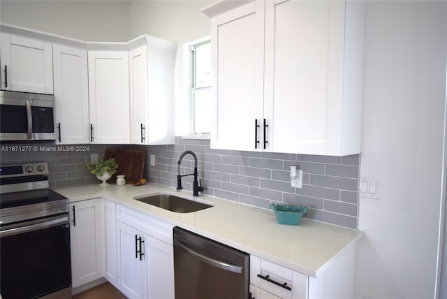 kitchen with white cabinets, appliances with stainless steel finishes, backsplash, and sink