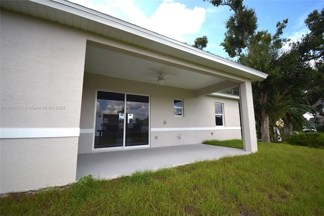 back of property with a lawn, a patio area, and ceiling fan