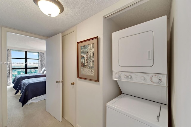 washroom with a textured ceiling, light colored carpet, and stacked washing maching and dryer