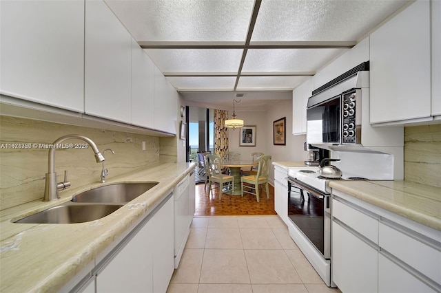 kitchen with decorative light fixtures, white appliances, sink, and white cabinets