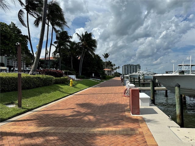 view of property's community featuring a boat dock, a lawn, and a water view