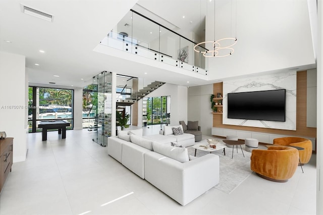 living room featuring a wall of windows, pool table, a chandelier, and a towering ceiling