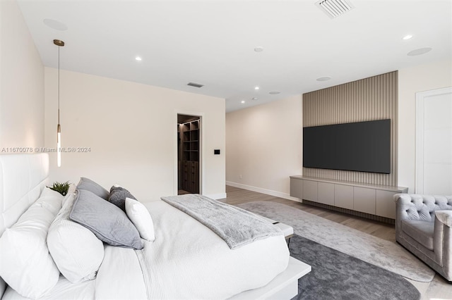 bedroom with light hardwood / wood-style flooring and a spacious closet