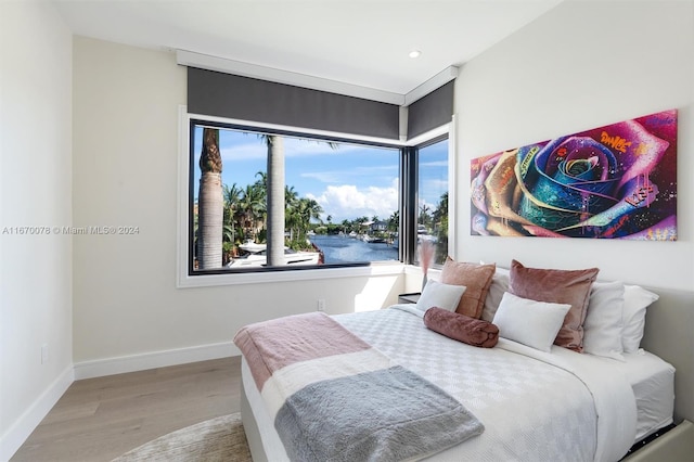 bedroom featuring light hardwood / wood-style floors and a water view