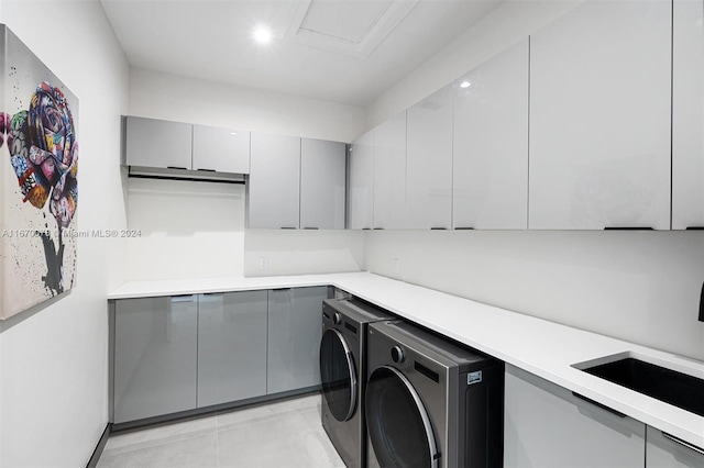 clothes washing area with cabinets, separate washer and dryer, and sink