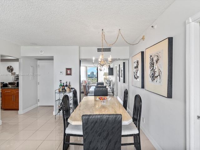 dining room featuring an inviting chandelier, light tile patterned floors, and a textured ceiling