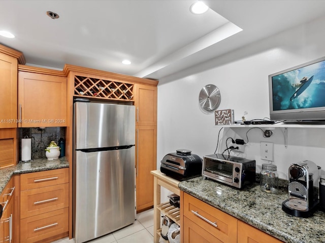 kitchen with light stone countertops, light tile patterned flooring, and stainless steel fridge