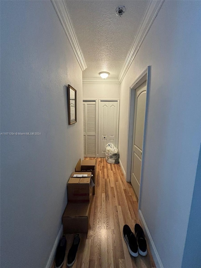 hall with ornamental molding, a textured ceiling, and hardwood / wood-style flooring