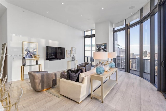 living room with light hardwood / wood-style floors, a high ceiling, and expansive windows