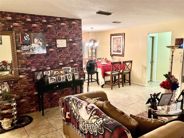 tiled living room featuring a textured ceiling, an inviting chandelier, and brick wall