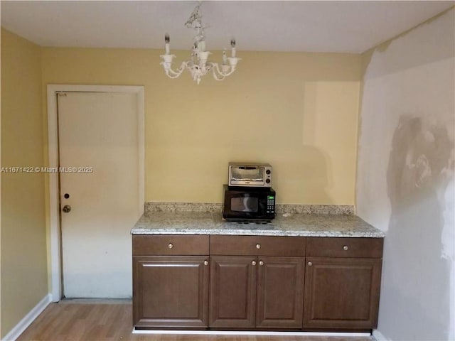 kitchen featuring light hardwood / wood-style floors, light stone counters, and a chandelier