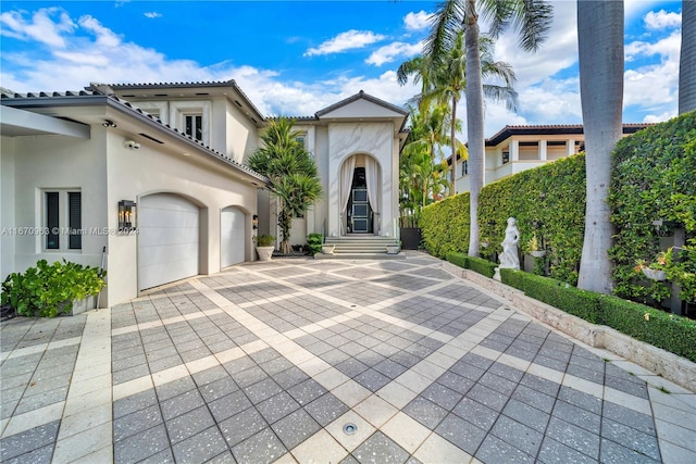 mediterranean / spanish home with an attached garage, driveway, and stucco siding