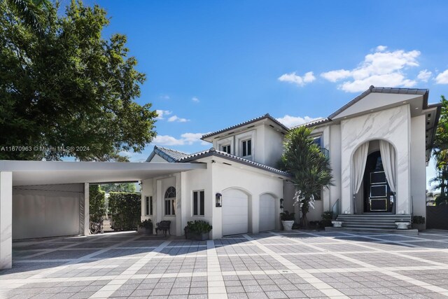 mediterranean / spanish house featuring stucco siding, decorative driveway, a tiled roof, and an attached garage