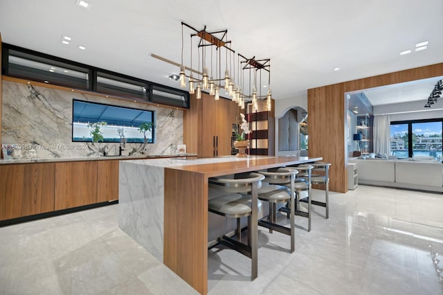 bar featuring arched walkways, backsplash, hanging light fixtures, and marble finish floor
