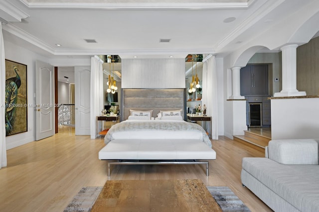 bedroom with crown molding, a notable chandelier, light wood-type flooring, and decorative columns