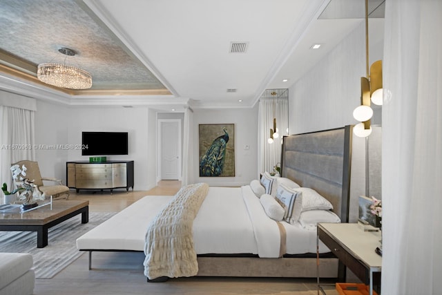 bedroom featuring crown molding, visible vents, wood finished floors, and a tray ceiling