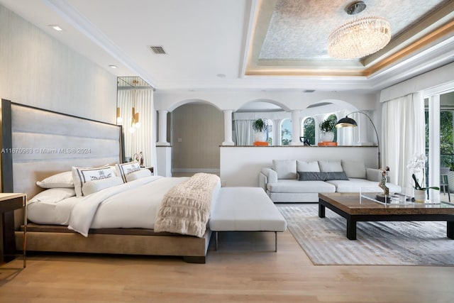 bedroom featuring visible vents, ornamental molding, wood finished floors, and a tray ceiling