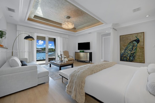 bedroom featuring ornamental molding, access to exterior, a tray ceiling, and light wood-type flooring