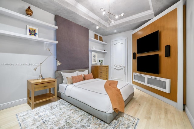 bedroom featuring a notable chandelier, light hardwood / wood-style floors, and a raised ceiling