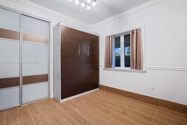 unfurnished bedroom with crown molding, a textured ceiling, a closet, and wood-type flooring