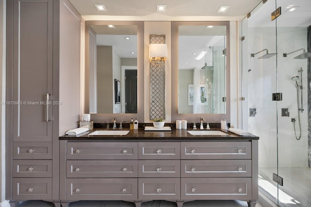 bathroom featuring double vanity, a stall shower, and a sink