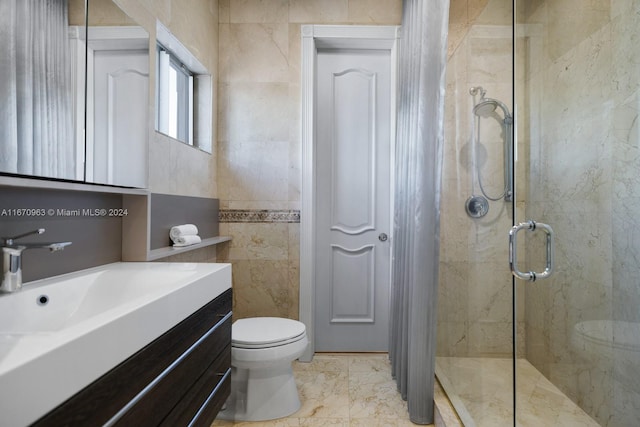 bathroom with tile walls, vanity, a shower with shower door, and toilet